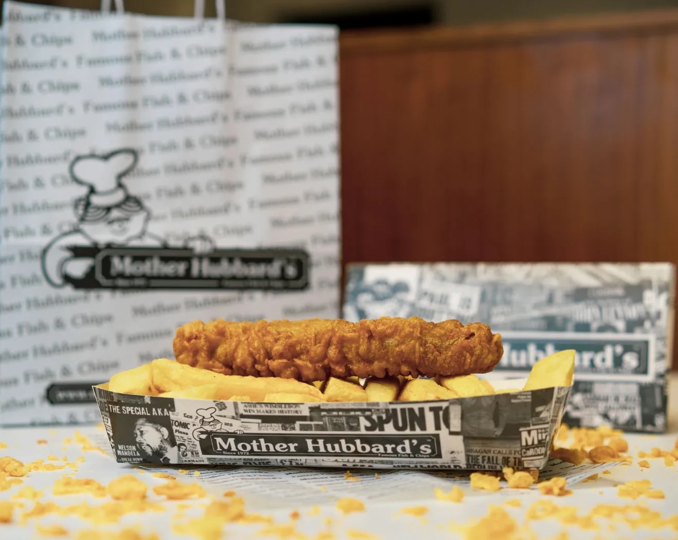 A battered sausage on chips in a Mother Hubbard’s paper tray
