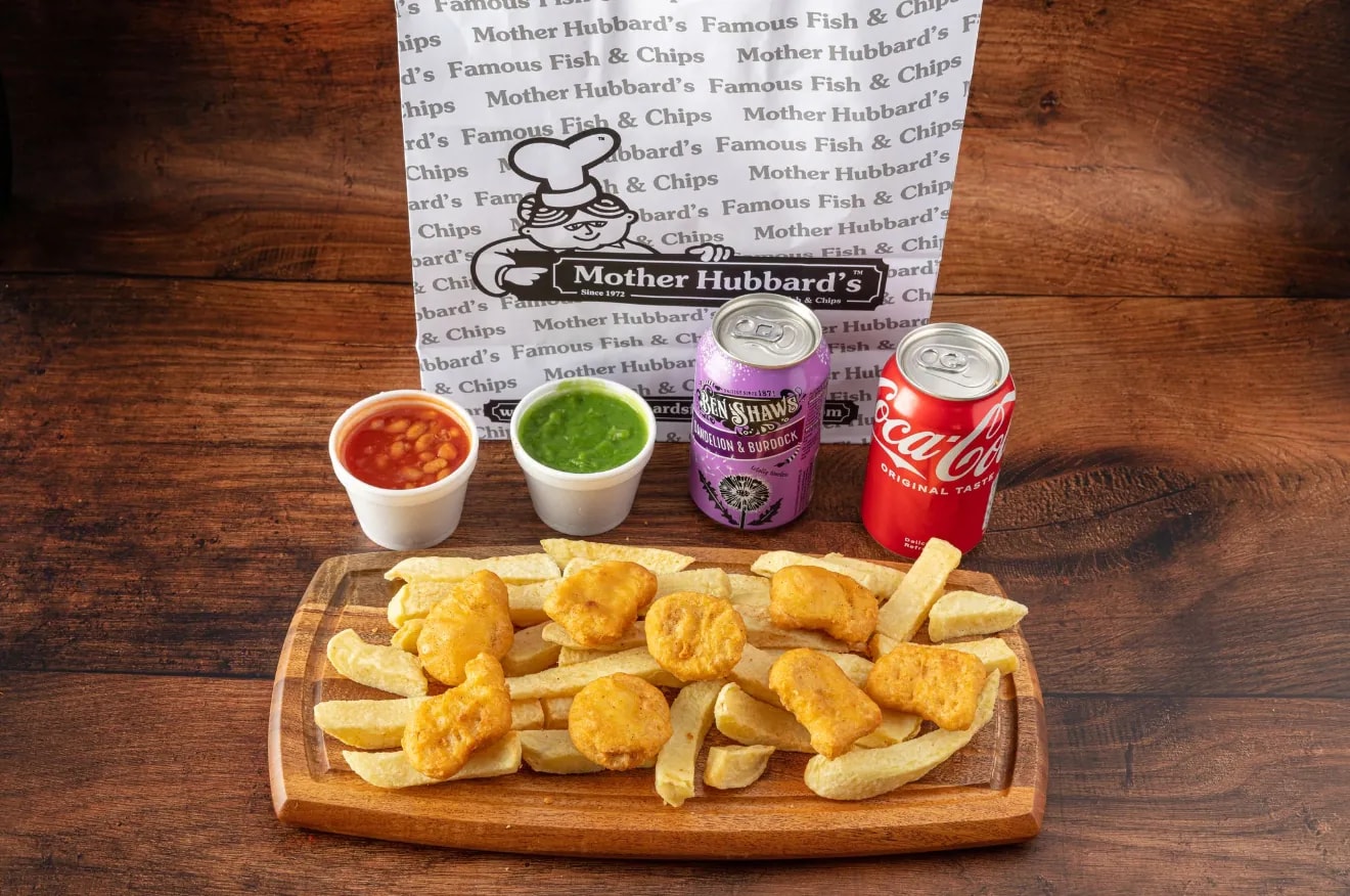 Chicken nuggets on chips on a wooden board, with beans, mushy peas and two cans
