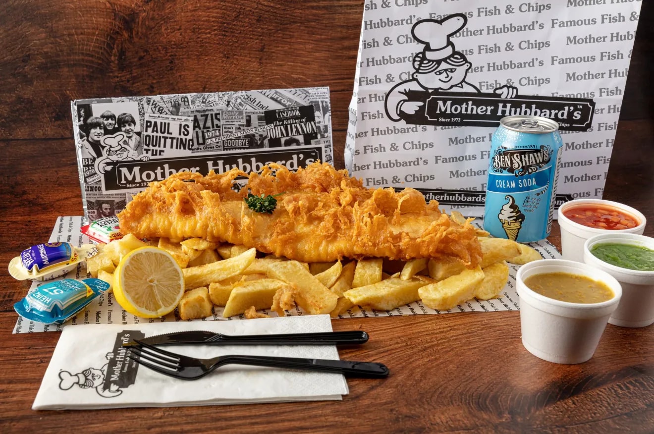 Battered fish and chips with a lemon wedge, curry sauce, mushy peas and a can of Ben Shaw’s cream soda