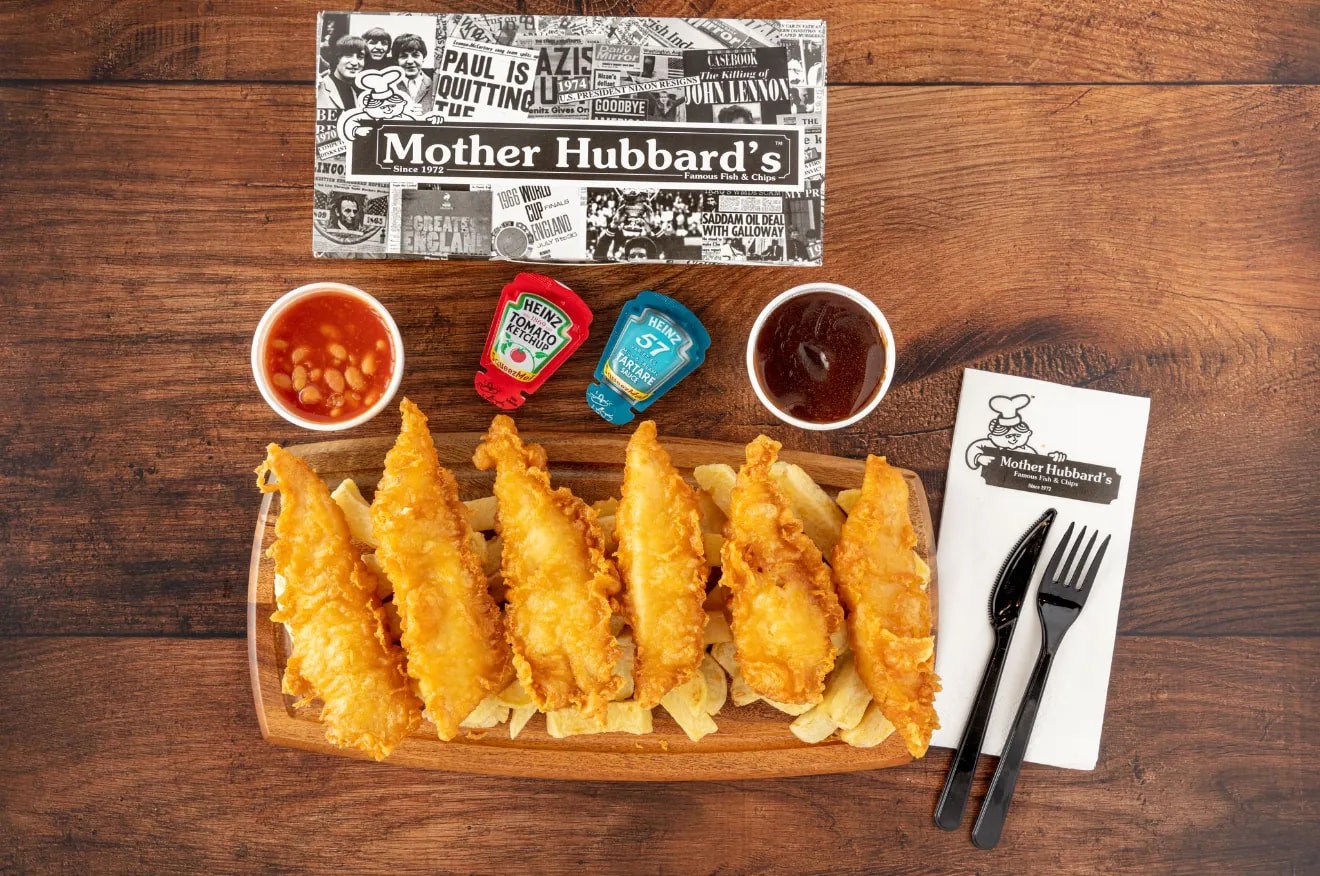 Fish bites on chips on a wooden board, with beans, gravy and sauce sachets