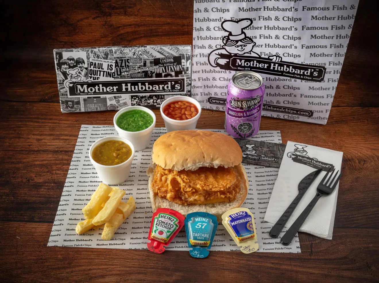 A fish cake butty with chips, mushy peas, curry sauce, beans and sauce sachets