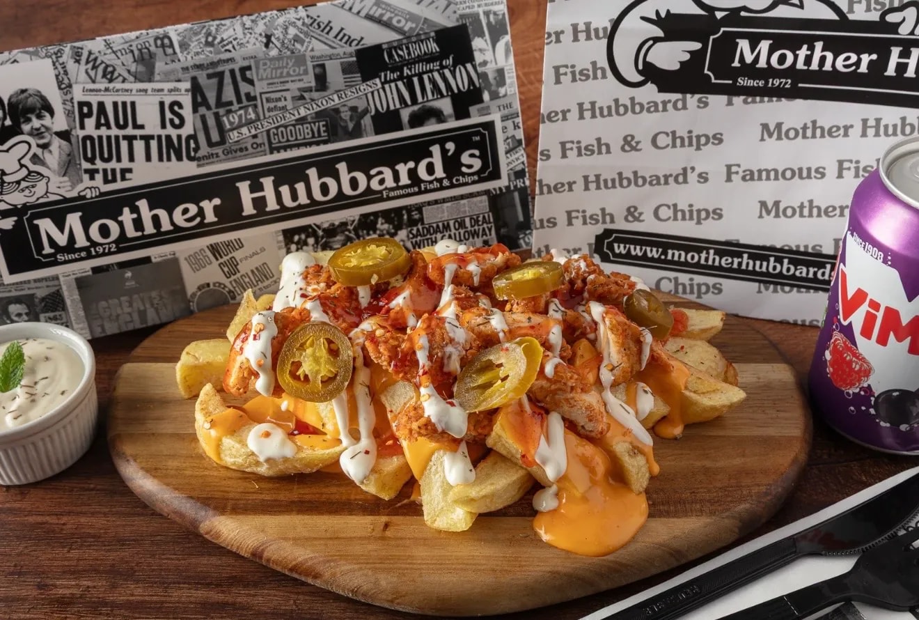 Chips loaded with crispy chicken, cheese sauce, mayonnaise and jalapeños on a wooden board