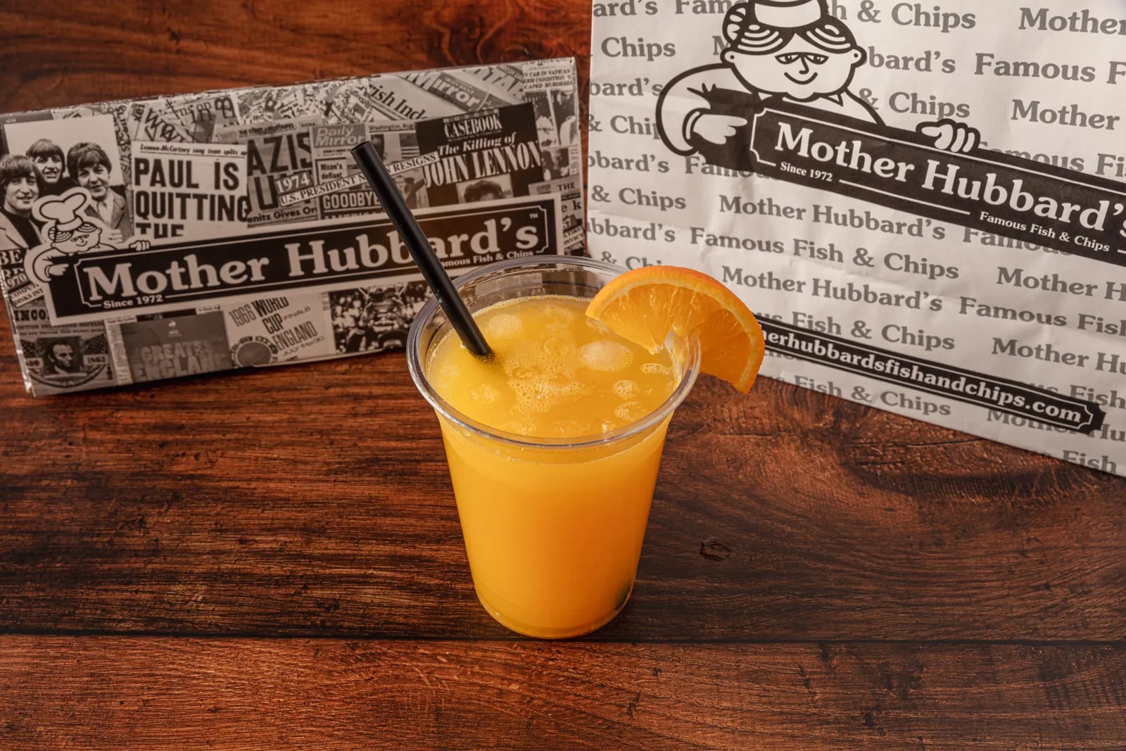 A glass of fresh orange juice with ice, a straw and an orange slice