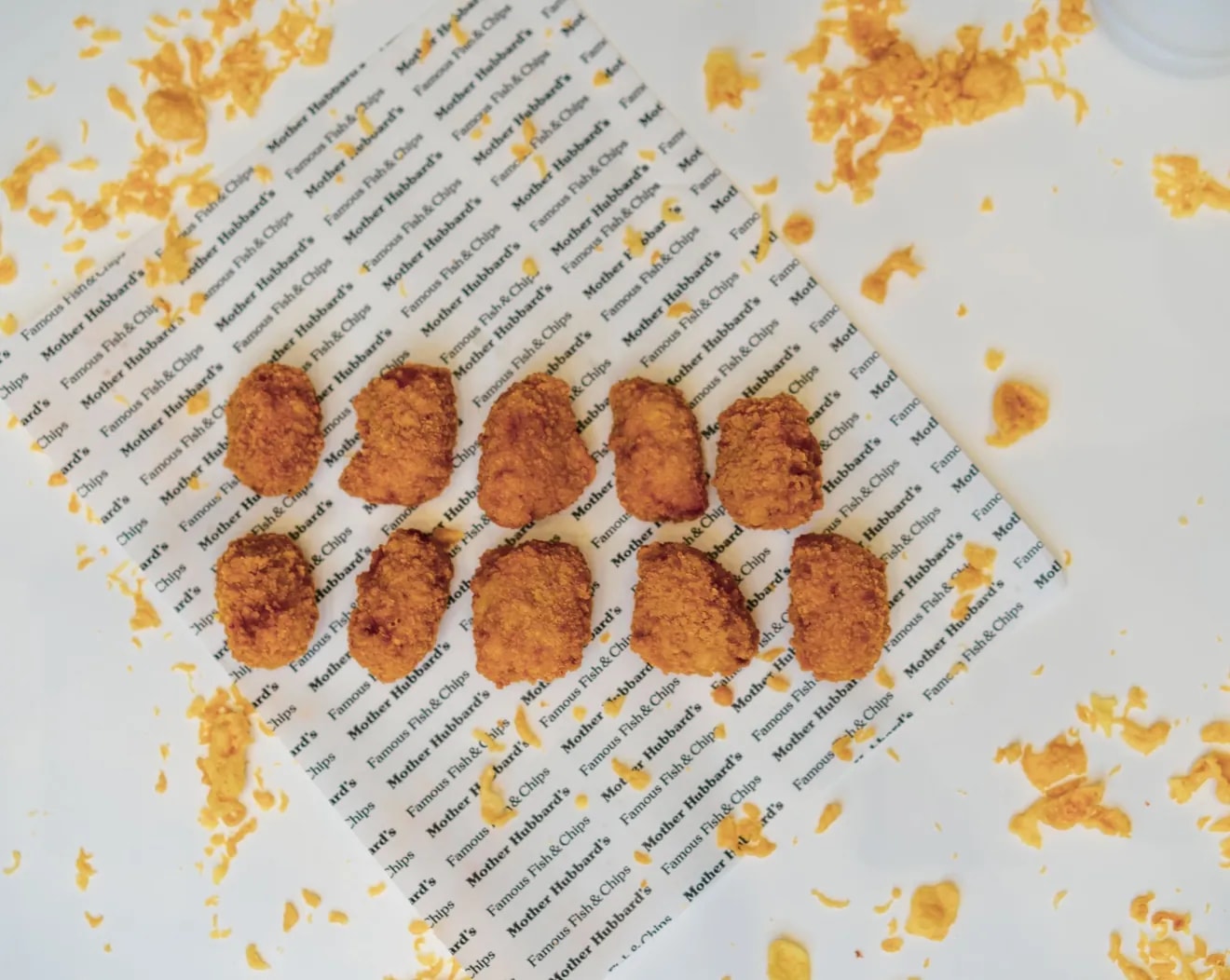 Breaded scampi laid out in two rows on Mother Hubbard’s printed paper