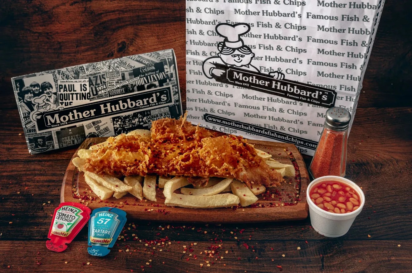 Spicy coated fish on chips with beans, chilli flakes and sauce sachets