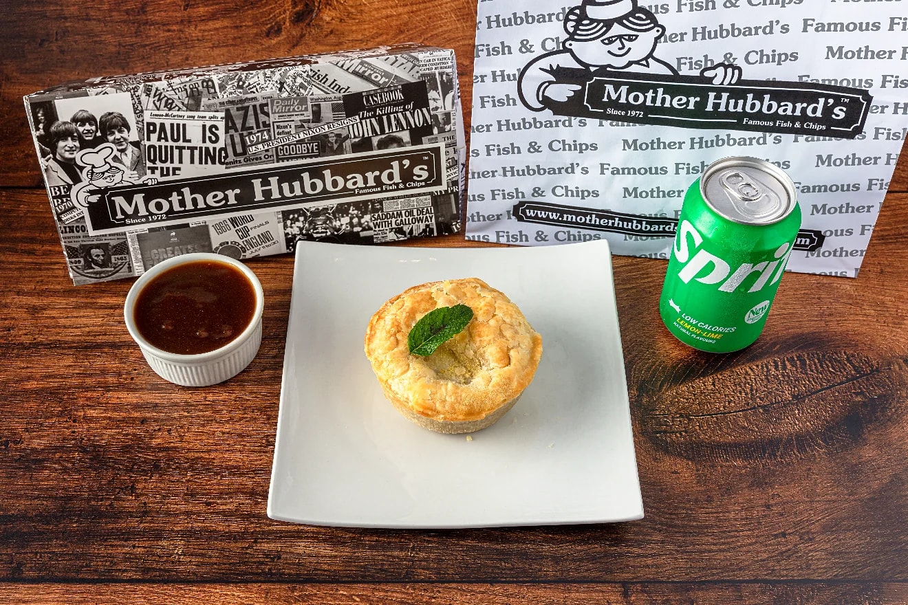 A steak pie on a white plate with gravy