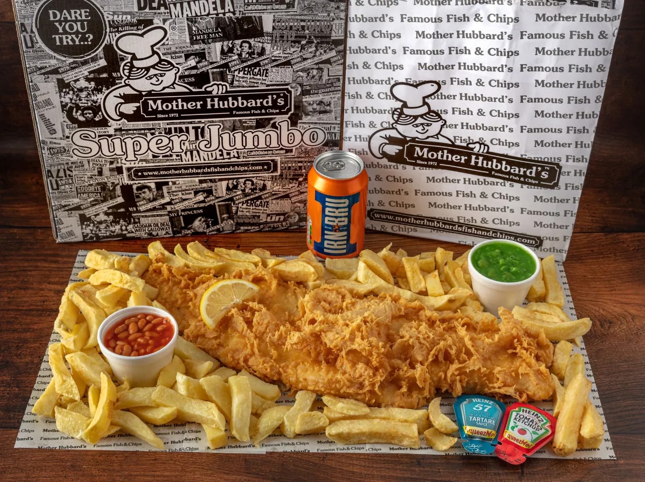 A super jumbo battered fish across a full tray of chips, with beans, mushy peas and Irn-Bru