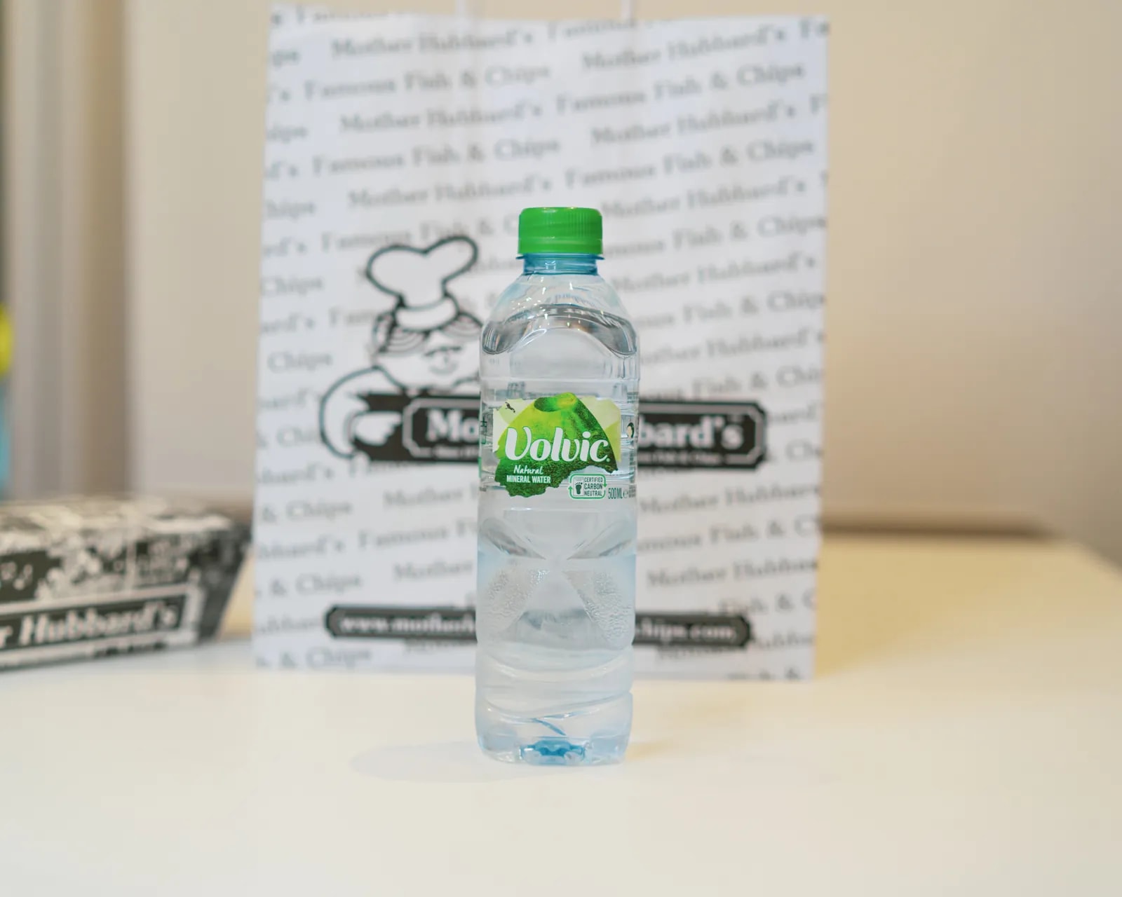 A bottle of Volvic water in front of Mother Hubbard’s printed paper