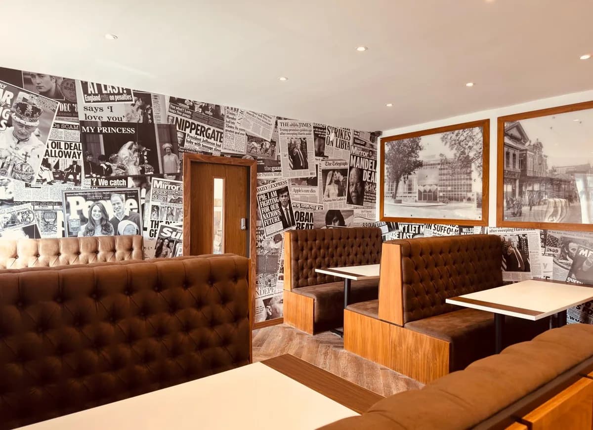 Brown leather booths against a wall of black-and-white front pages